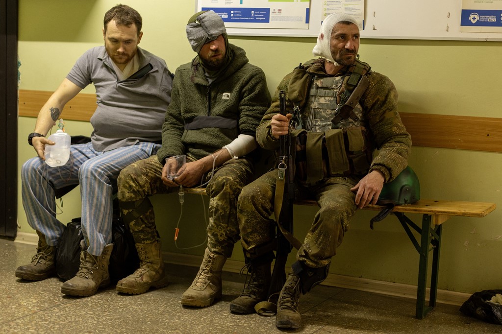 Ukrainian volunteer soldiers sit on a bench inside the hospital in Bakhmut